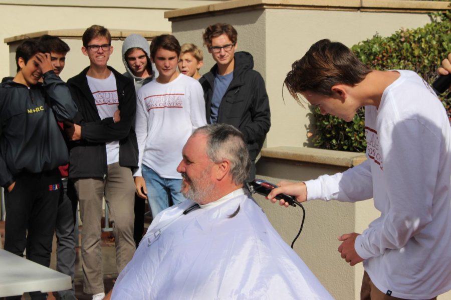 The varsity cross country team watches as Logan Brooks shaves Coach Wittkop’s head in front of the whole school at lunch. In the beginning of the season, Wittkop promised his players that if they won CIF and state they could shave his head.