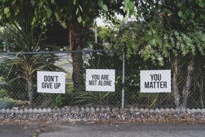 (“Don’t give up. You are not alone, You matter signage on metal fence” by Dan Meyers, licensed under Unsplash License).